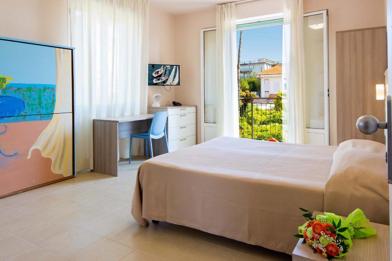 een slaapkamer met een bed, een bureau en een raam bij Hotel Villa San Giuseppe in San Bartolomeo al Mare