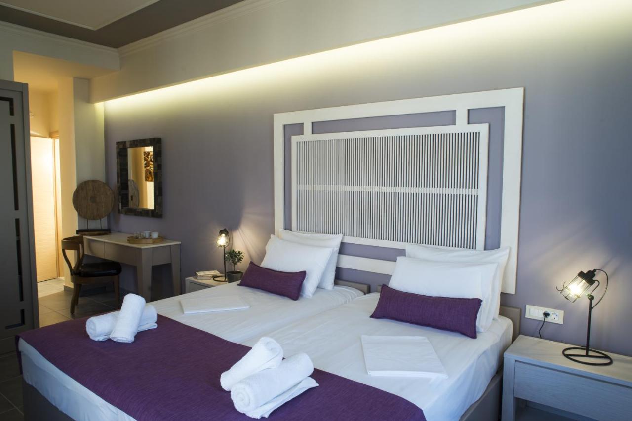 een slaapkamer met twee bedden met witte lakens en paarse kussens bij Elia Potie in Chania