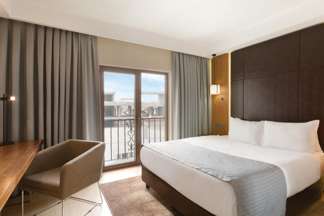een hotelkamer met een bed, een bureau en een raam bij Ramada by Wyndham Istanbul Florya in Istanbul
