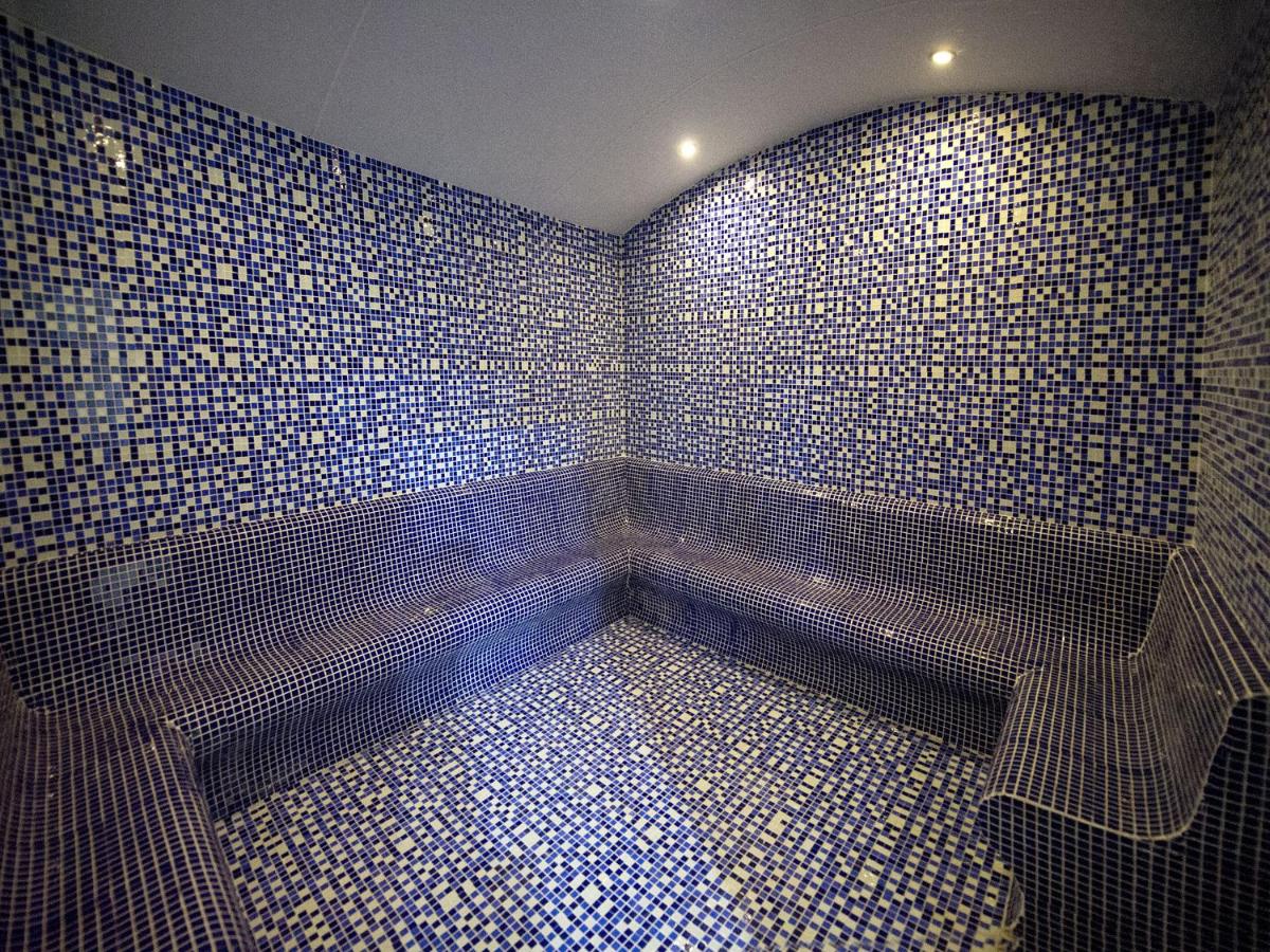 een badkamer met blauwe tegelwanden en een bankje bij Ramada by Wyndham Istanbul Florya in Istanbul