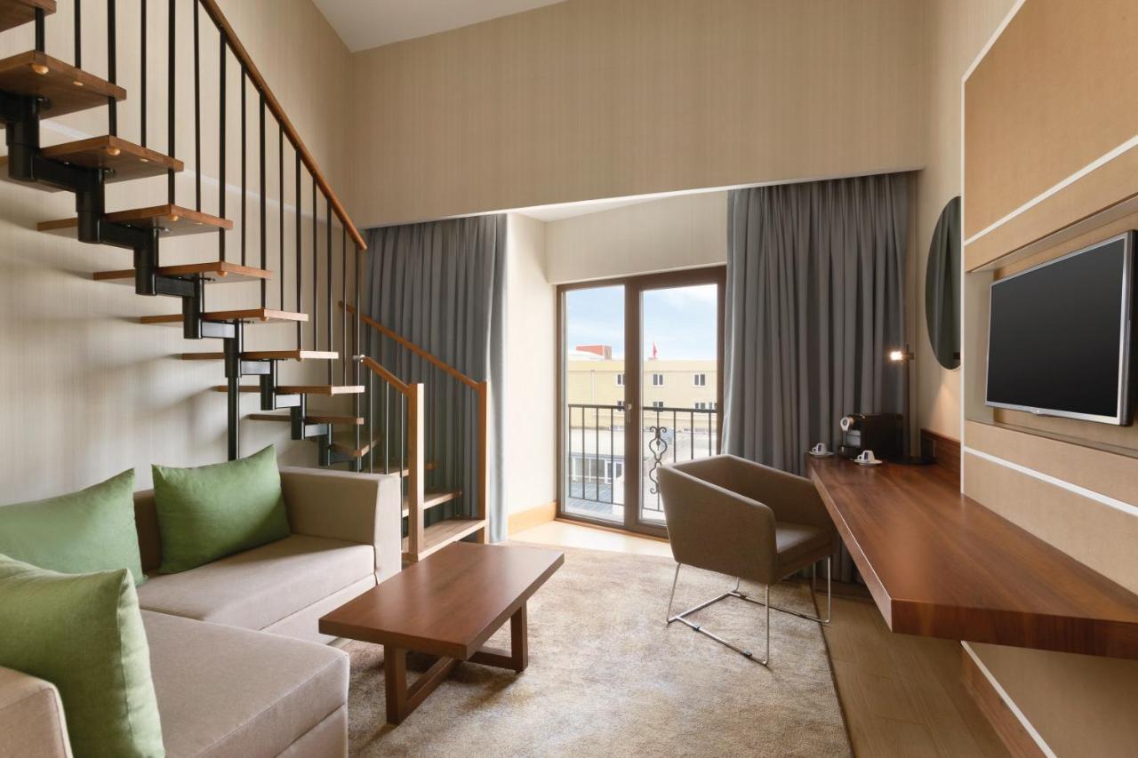 een woonkamer met een bank en een trap met een televisie bij Ramada by Wyndham Istanbul Florya in Istanbul