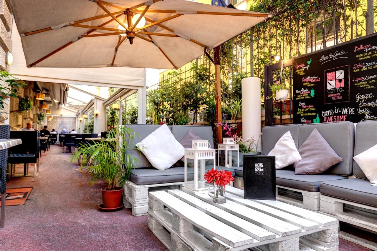 een restaurant met banken, een tafel en een parasol bij Dharma Luxury Hotel & SPA in Rome
