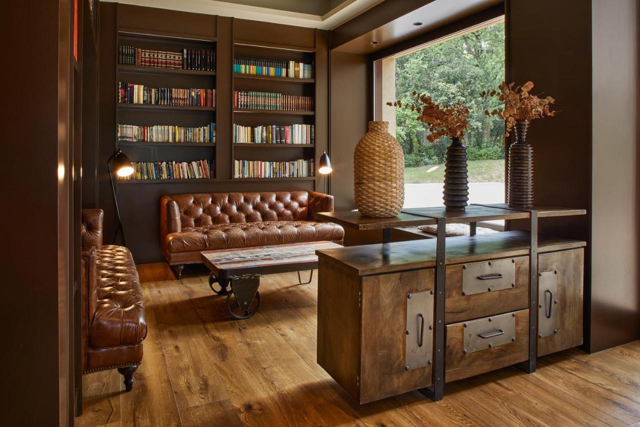 een woonkamer met een leren bank en een boekenkast bij Mas Salagros EcoResort & SPA in Vallromanas