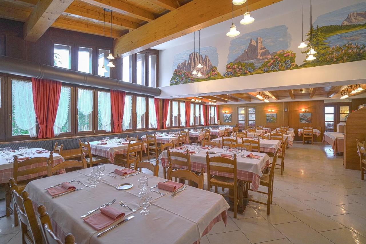 een eetkamer met witte tafels en stoelen en ramen bij GH Hotel Fratazza in San Martino di Castrozza