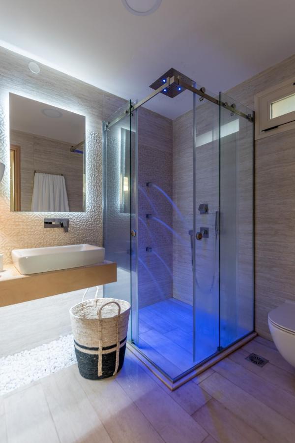 een badkamer met een glazen douchecabine, een badkuip en een wastafel bij Stelios Gardens in Malia