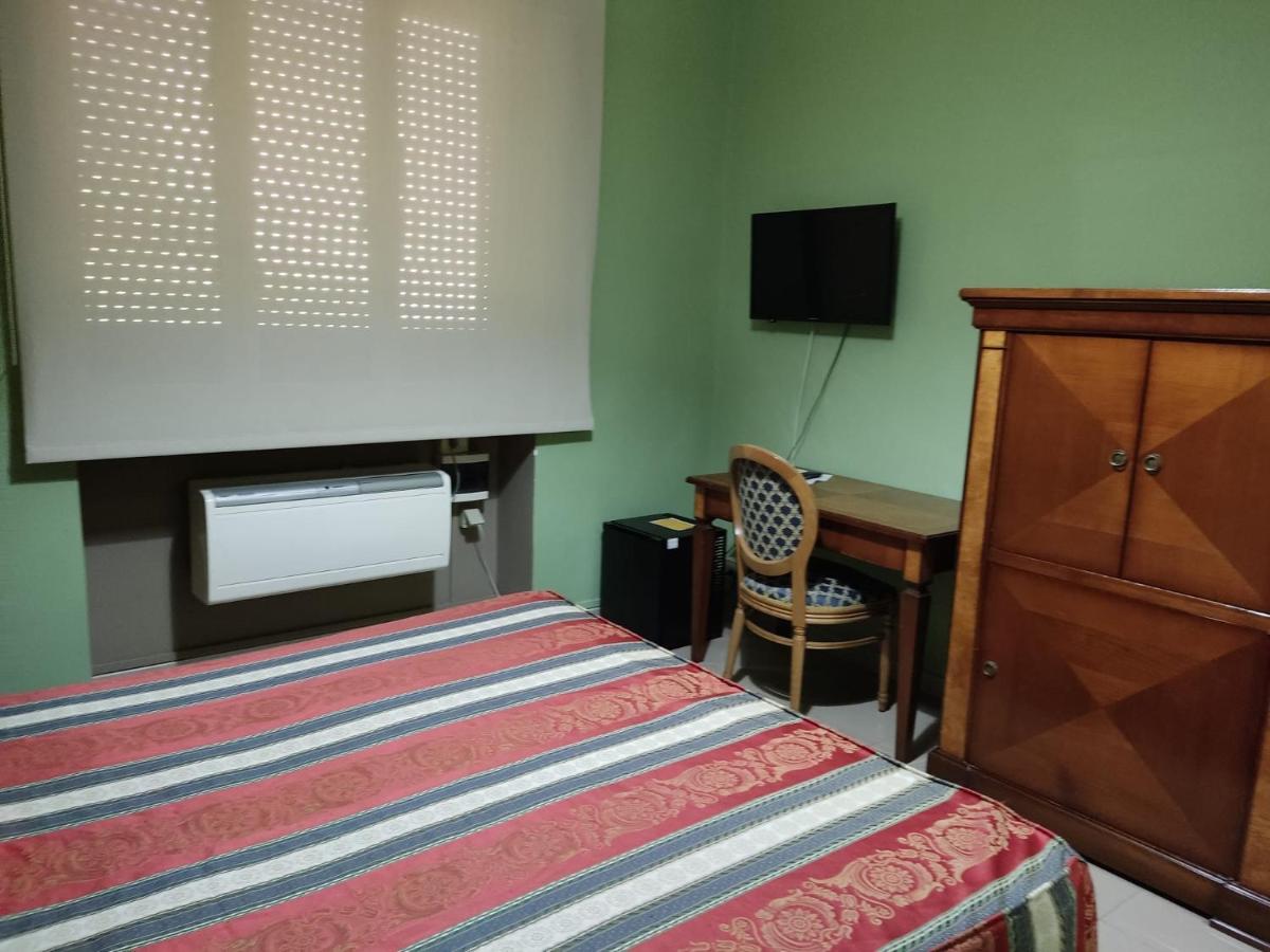 een slaapkamer met een bed, een tv en een bureau bij Hotel Plaza in Taranto