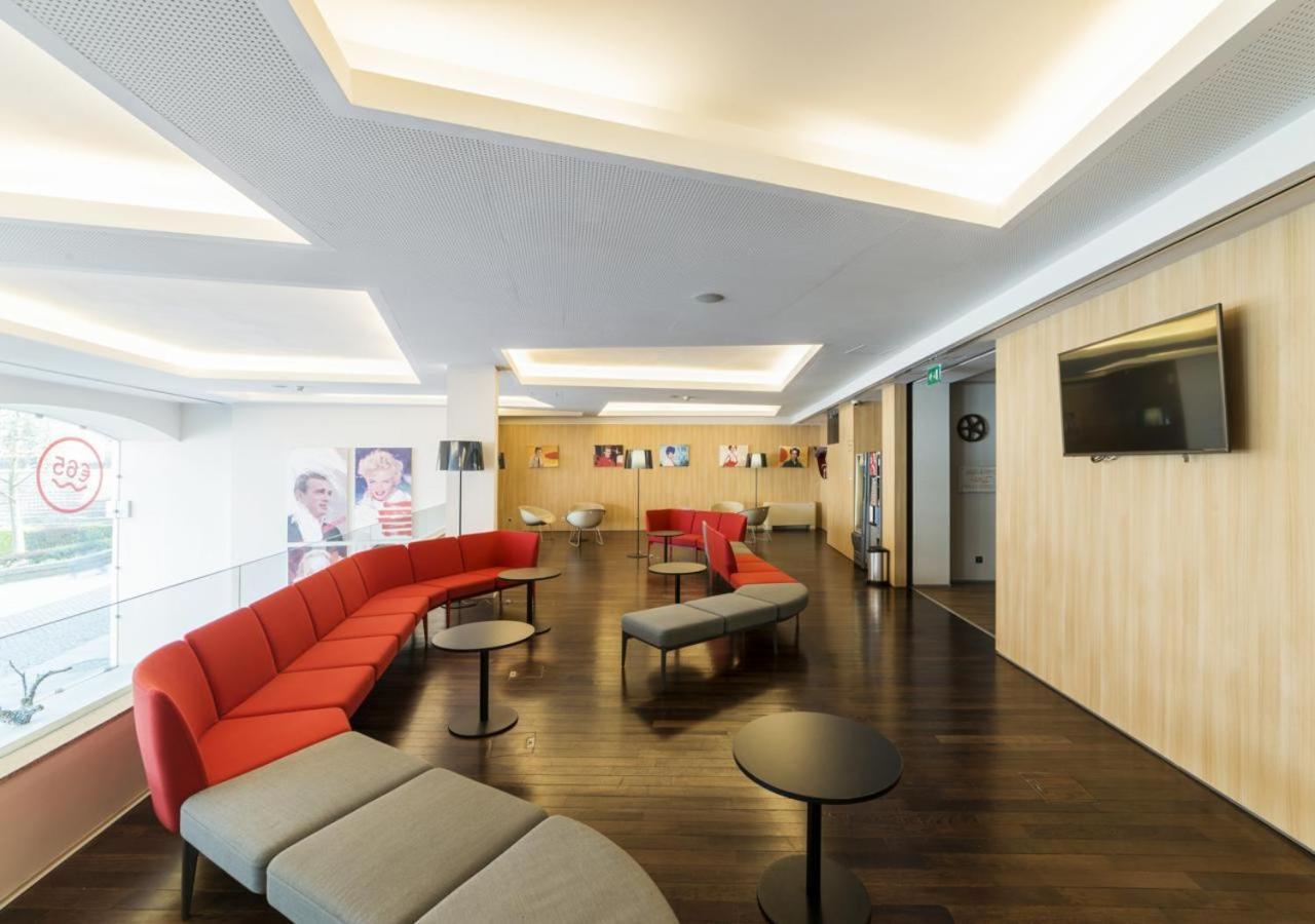 een wachtkamer met een rode bank en een tv bij Moov Hotel Porto Centro in Porto