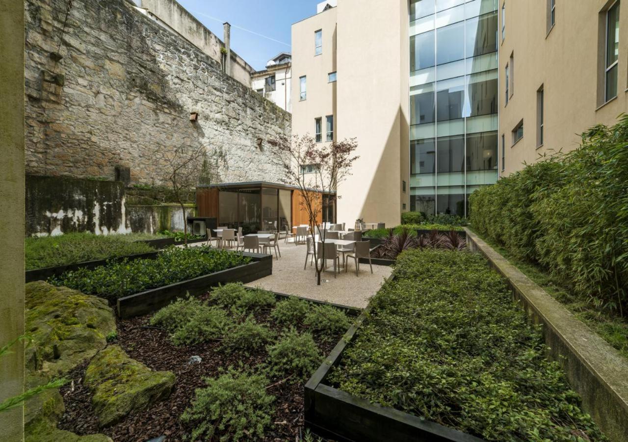 een tuin met tafels en stoelen naast een gebouw bij Moov Hotel Porto Centro in Porto