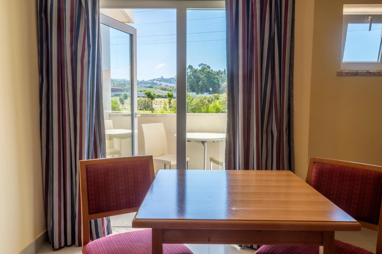 een eetkamer met een tafel en een groot raam bij Amazonia Palmela Apartamentos Turisticos in Palmela