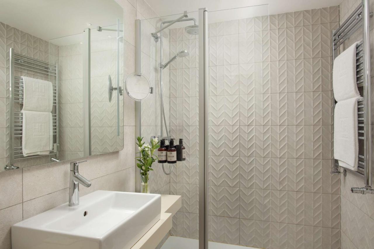 een witte badkamer met een wastafel en een douche bij NH Bologna De La Gare in Bologna