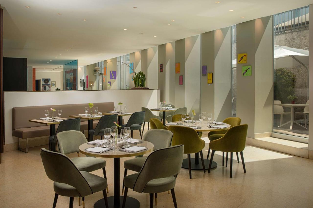 een restaurant met tafels en stoelen waarop wijnglazen staan bij NH Bergamo in Bergamo