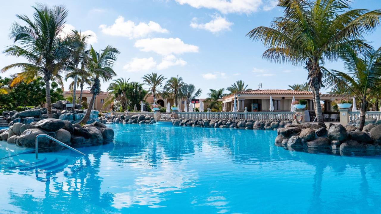 een zwembad in een resort met blauw water en palmbomen bij Palm Oasis Maspalomas in Maspalomas