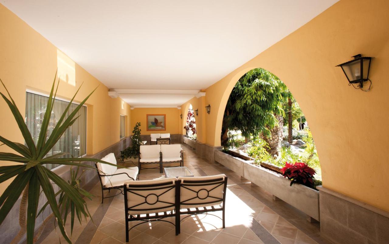 een hal met een tafel en stoelen en een groot raam bij Palm Oasis Maspalomas in Maspalomas