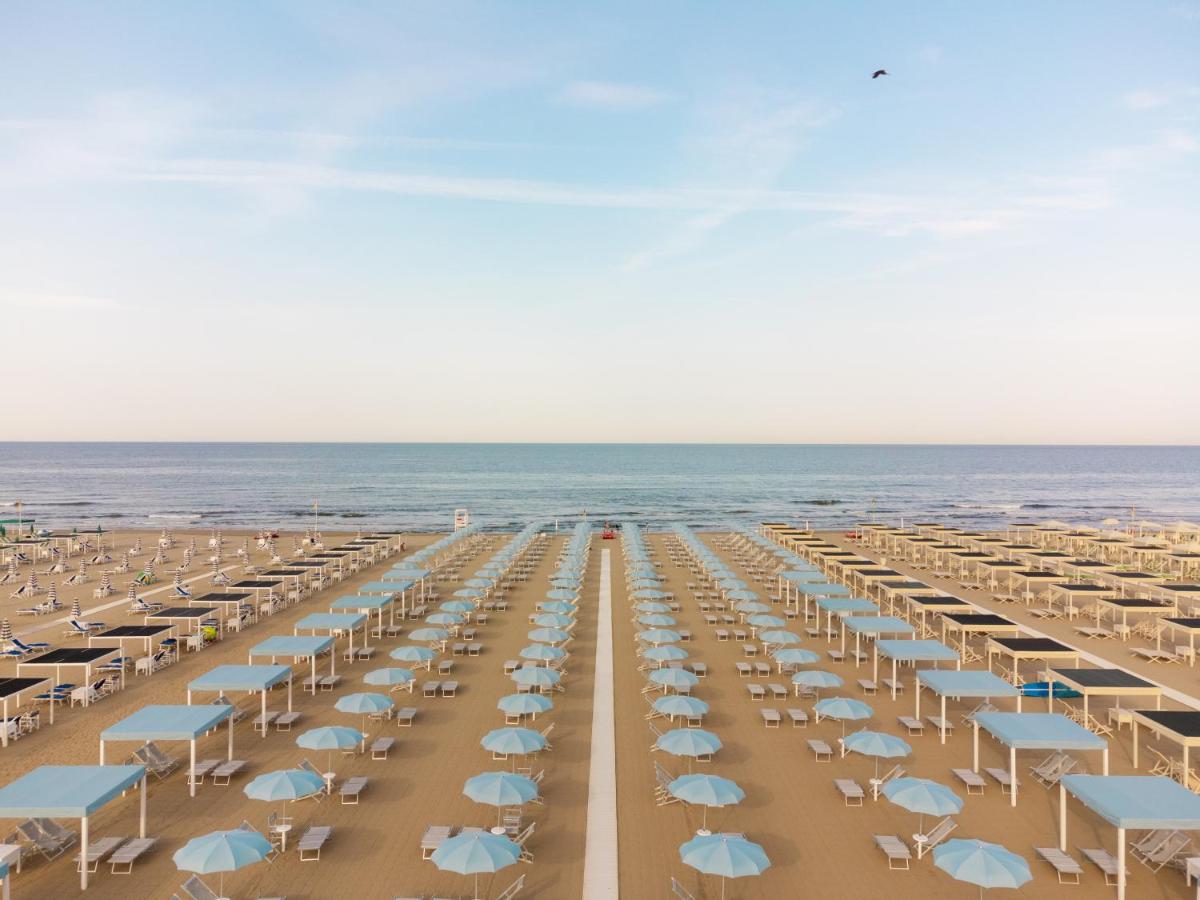 een strand met stoelen en parasols en de oceaan bij Re Versiliana Hotel in Marina di Pietrasanta