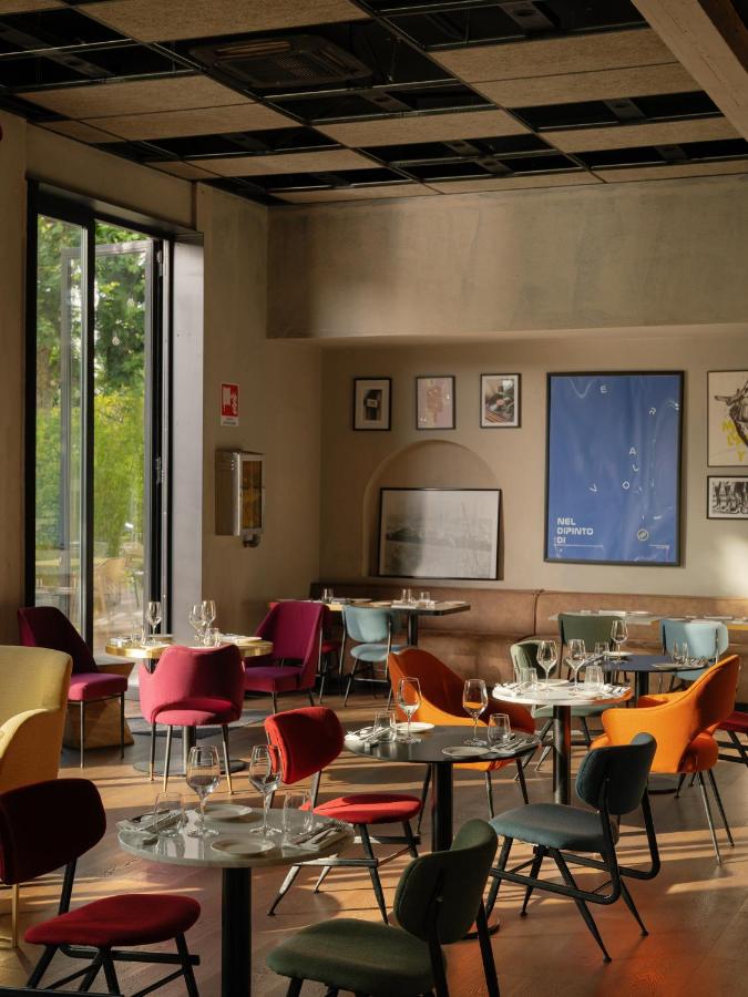 een restaurant met tafels en stoelen en een projectiescherm bij Re Versiliana Hotel in Marina di Pietrasanta
