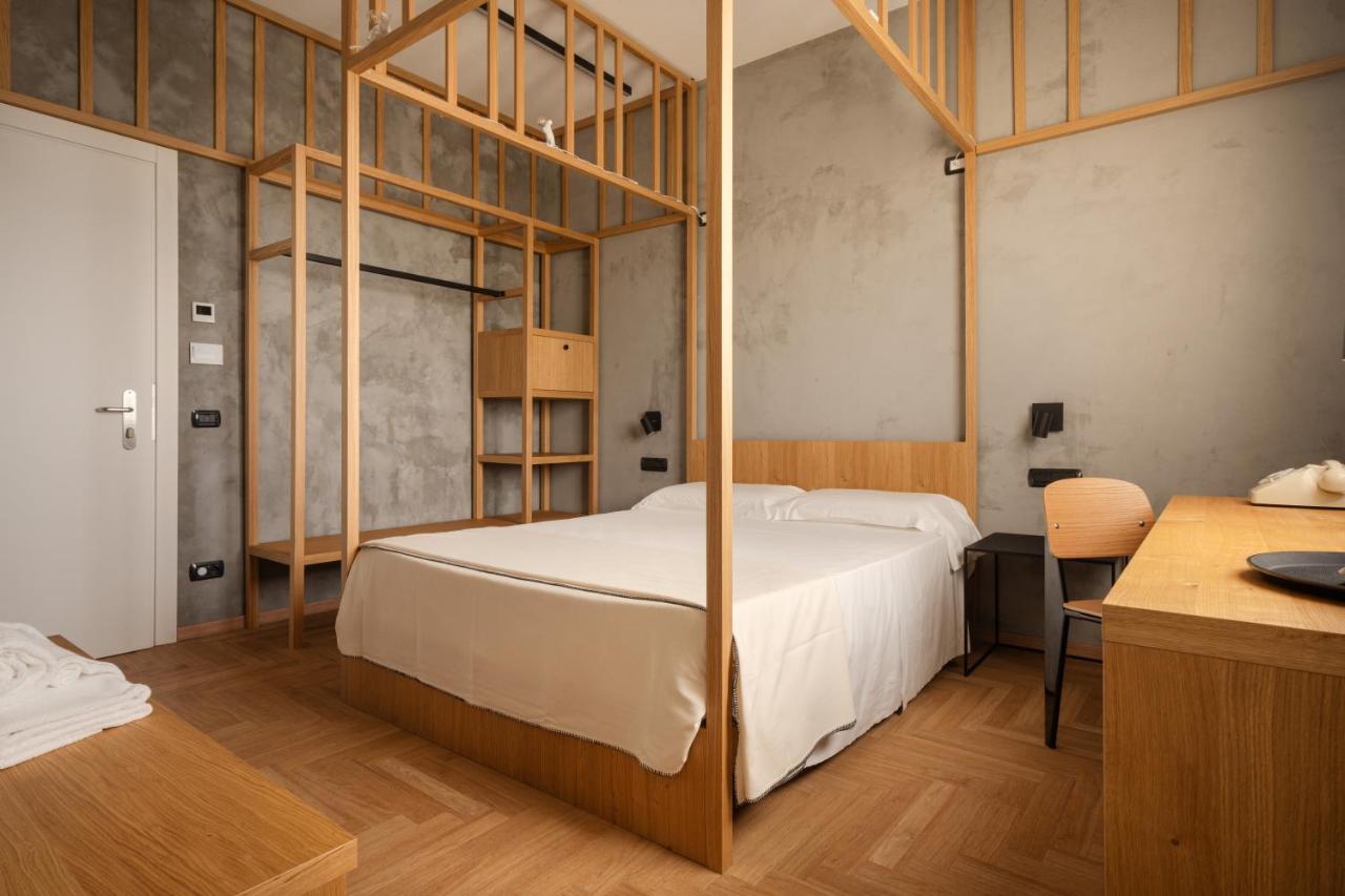 een slaapkamer met een bed met een houten frame bij Re Versiliana Hotel in Marina di Pietrasanta