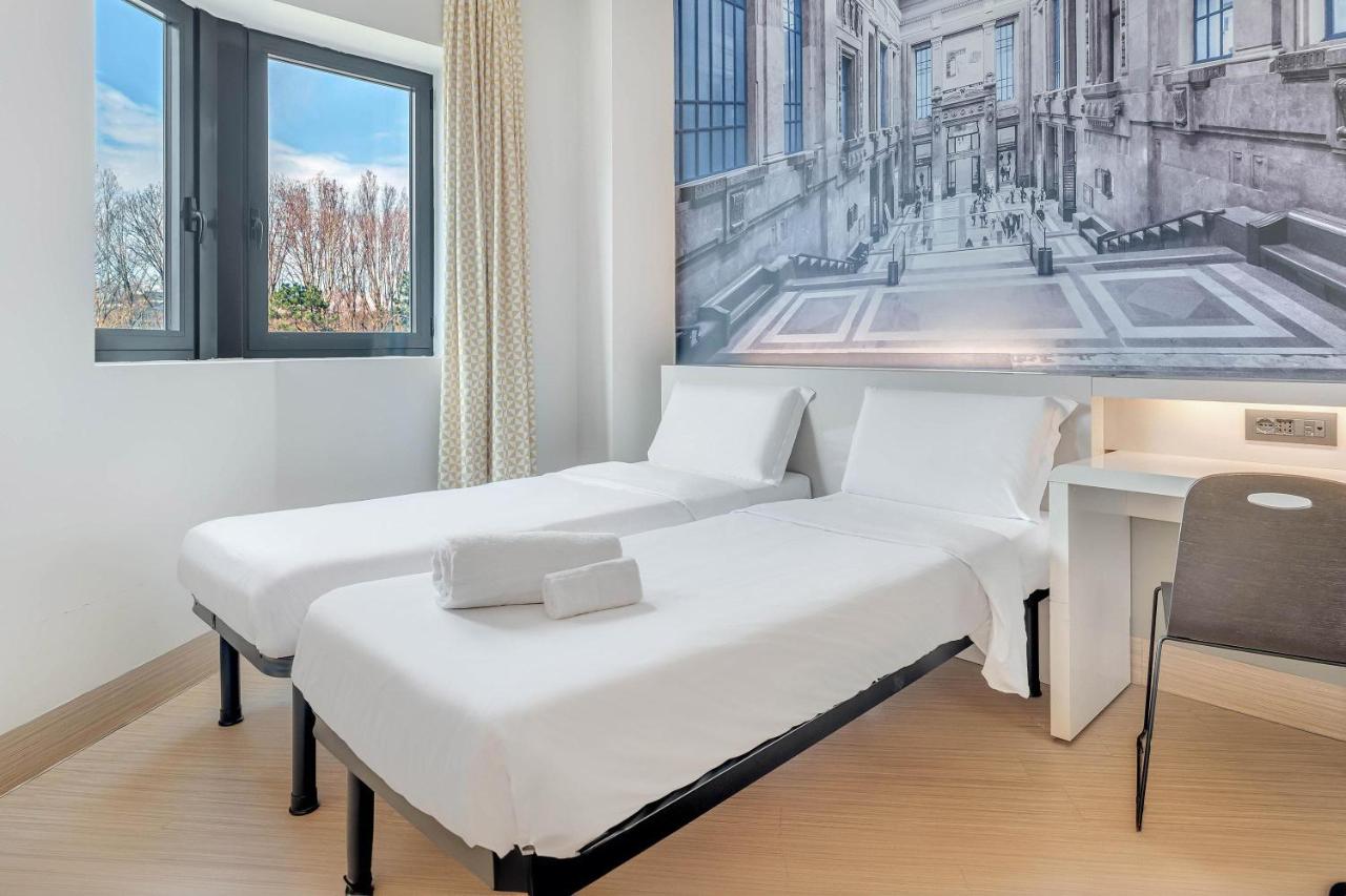 twee bedden in een kamer met een schilderij aan de muur bij B&B Hotel Milano San Siro in Milaan