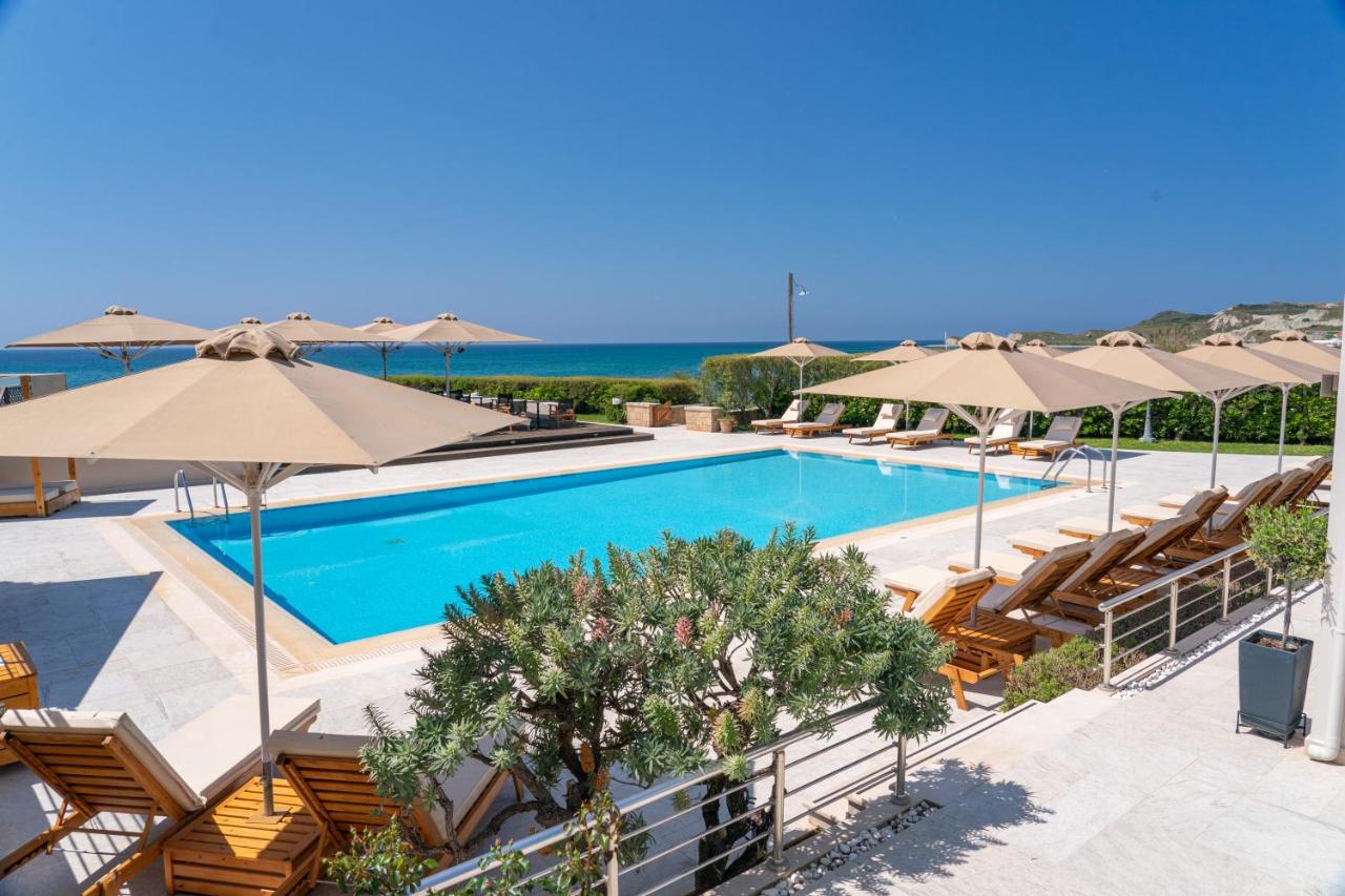 een zwembad met parasols en ligstoelen en de oceaan bij Costa Rossa Boutique Hotel - Adults Only in Lixouri