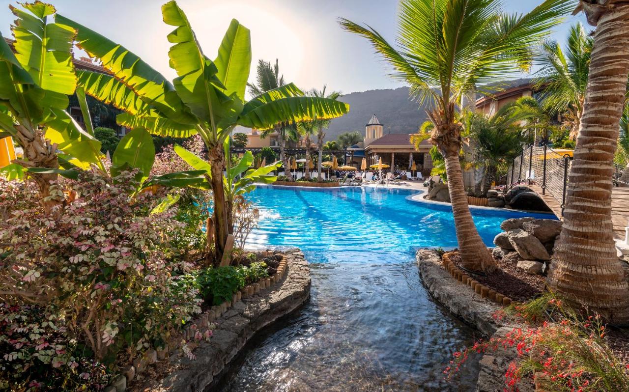 een zwembad met palmbomen in een resort bij Hotel Cordial Mogán Playa in Puerto de Mogán