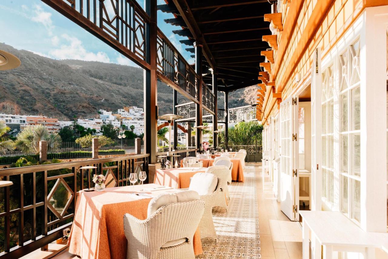 een restaurant met tafels en stoelen op een balkon bij Hotel Cordial Mogán Playa in Puerto de Mogán