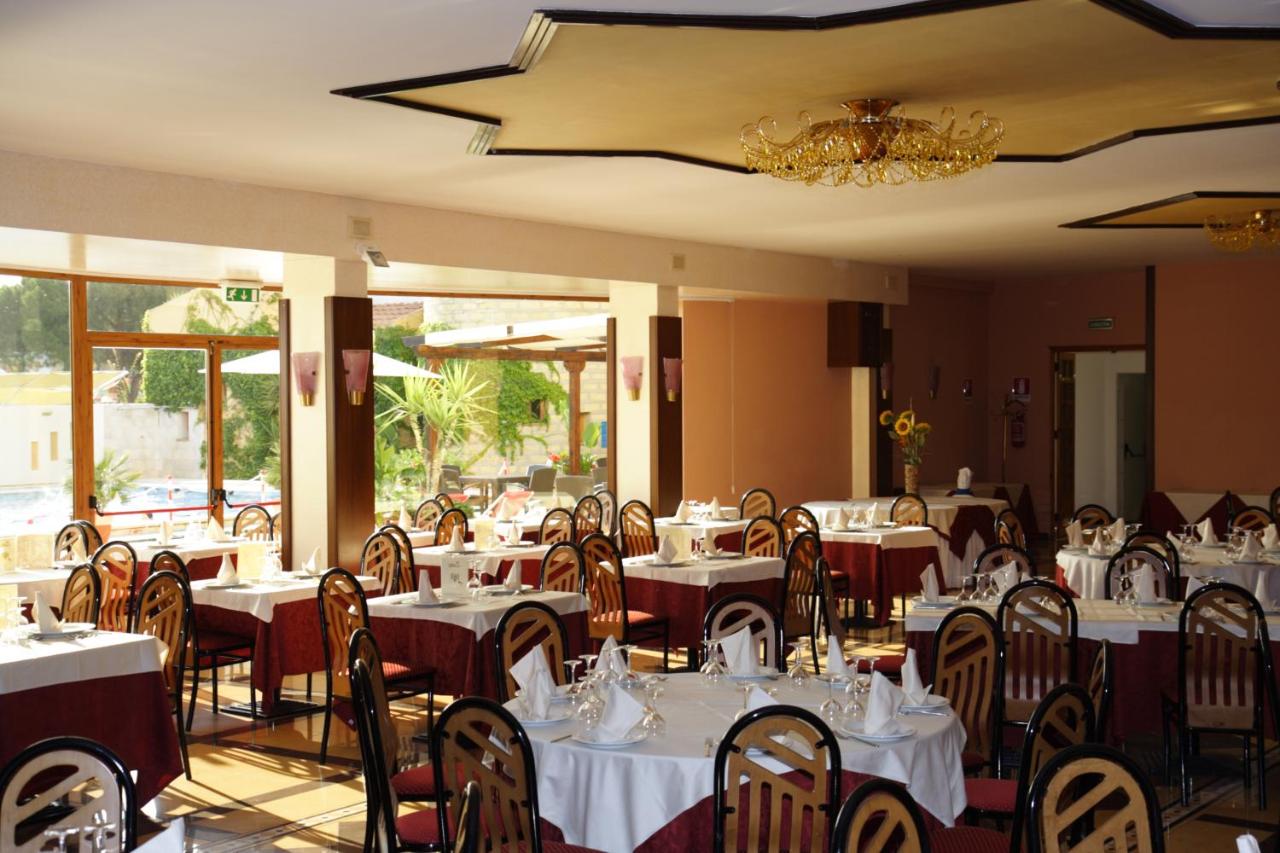 een restaurant met witte tafels en stoelen en een kroonluchter bij Hotel Tre Torri in Villaggio Mosè