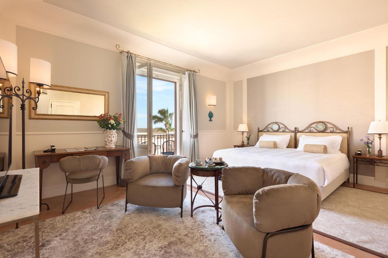 een slaapkamer met een bed, een bureau en stoelen bij Almar Giardino di Costanza Mazara del Vallo Resort & Spa in Mazara