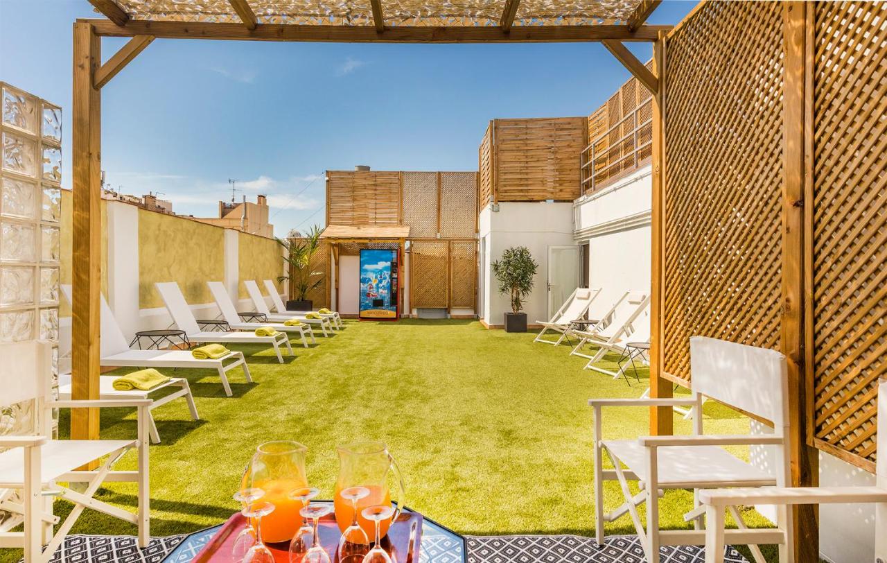 een terras met stoelen en een gazon met drankjes erop. bij Hotel Nouvel in Barcelona