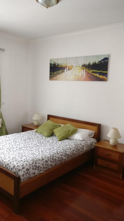 een slaapkamer met een bed, twee nachtkastjes en een schilderij aan de muur bij Ericeira Beach Haven in Ericeira