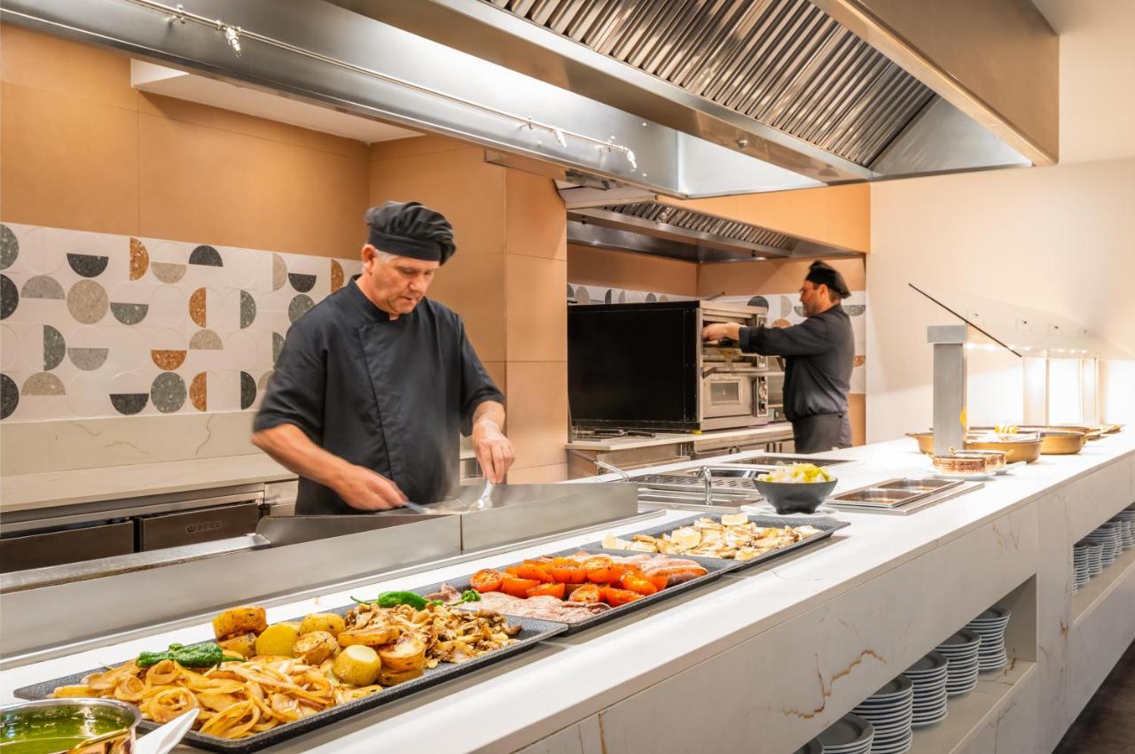 Een chef-kok die eten bereidt in een restaurantkeuken. bij The Place Mariner by ALEGRIA Adults Only in Lloret de Mar