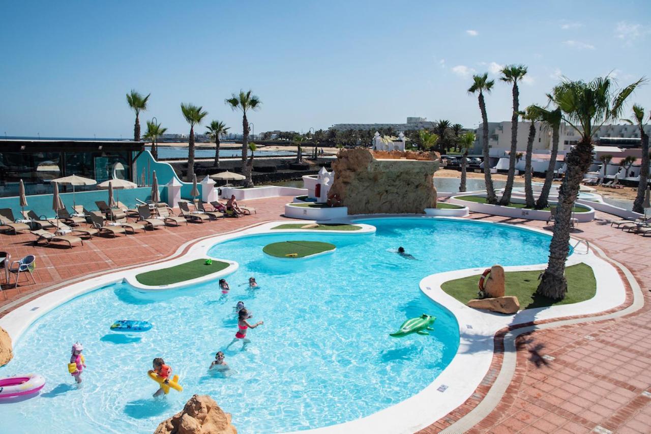 een groep mensen in een zwembad in een resort bij Sands Beach Resort in Costa Teguise