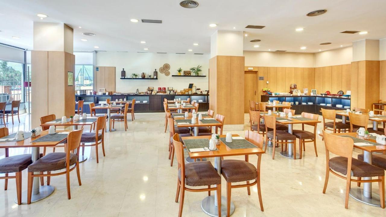 een eetkamer met houten tafels en stoelen bij Sercotel Porta Barcelona in Sant Just Desvern