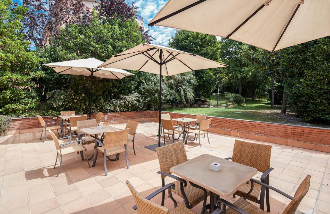 een terras buiten met tafels, stoelen en parasols bij Sercotel Porta Barcelona in Sant Just Desvern