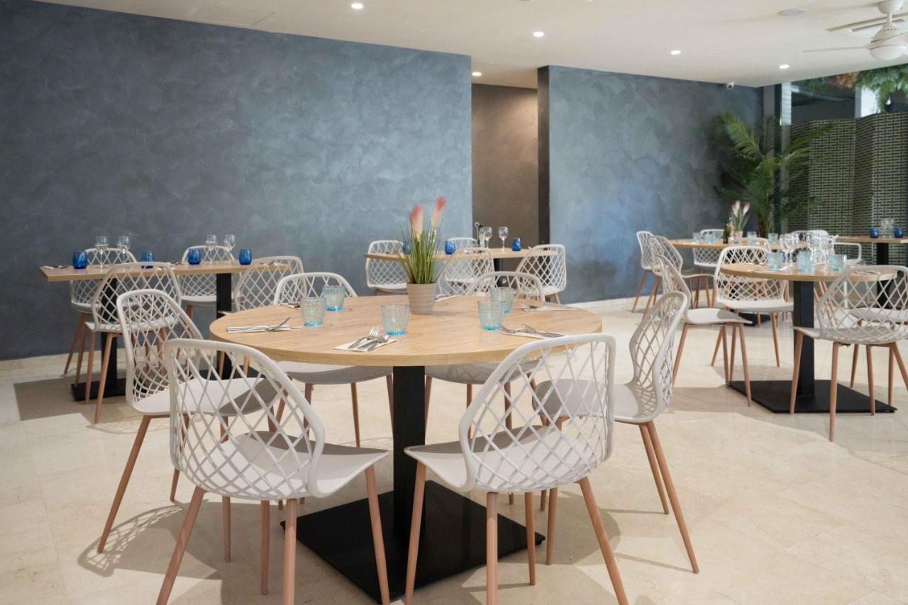 een eetkamer met tafels en witte stoelen bij Hotel Ciutat Martorell in Martorell