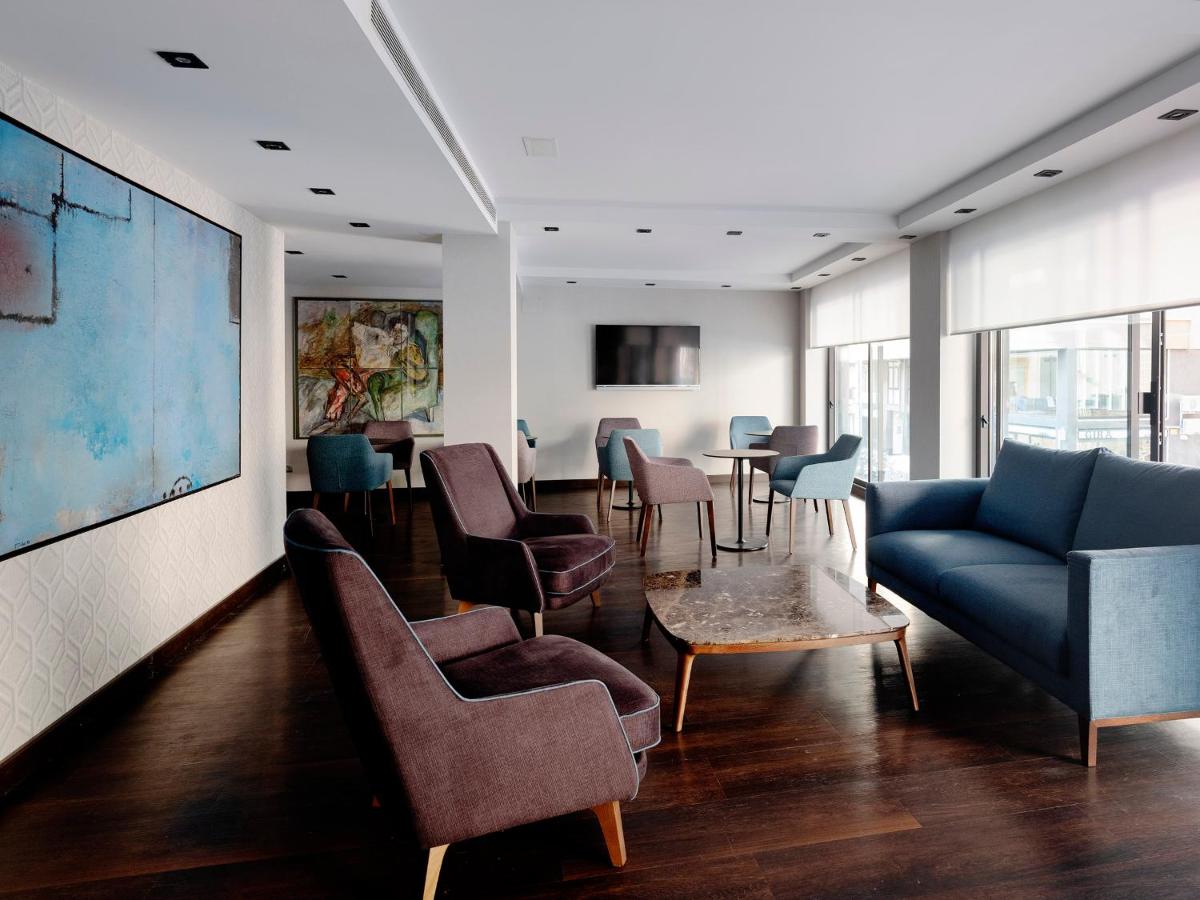 een woonkamer met een bank, stoelen en een tafel bij HG City Suites Barcelona in Barcelona