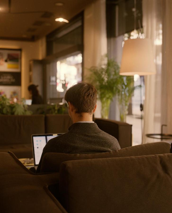 een man zit op een stoel met een laptop bij Pol & Grace Hotel in Barcelona