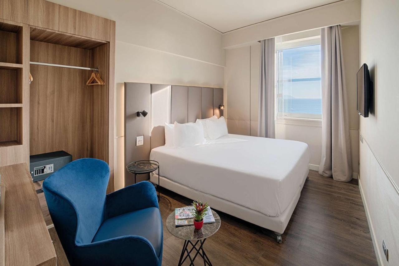 een hotelkamer met een bed en een blauwe stoel bij NH Napoli Panorama in Napels