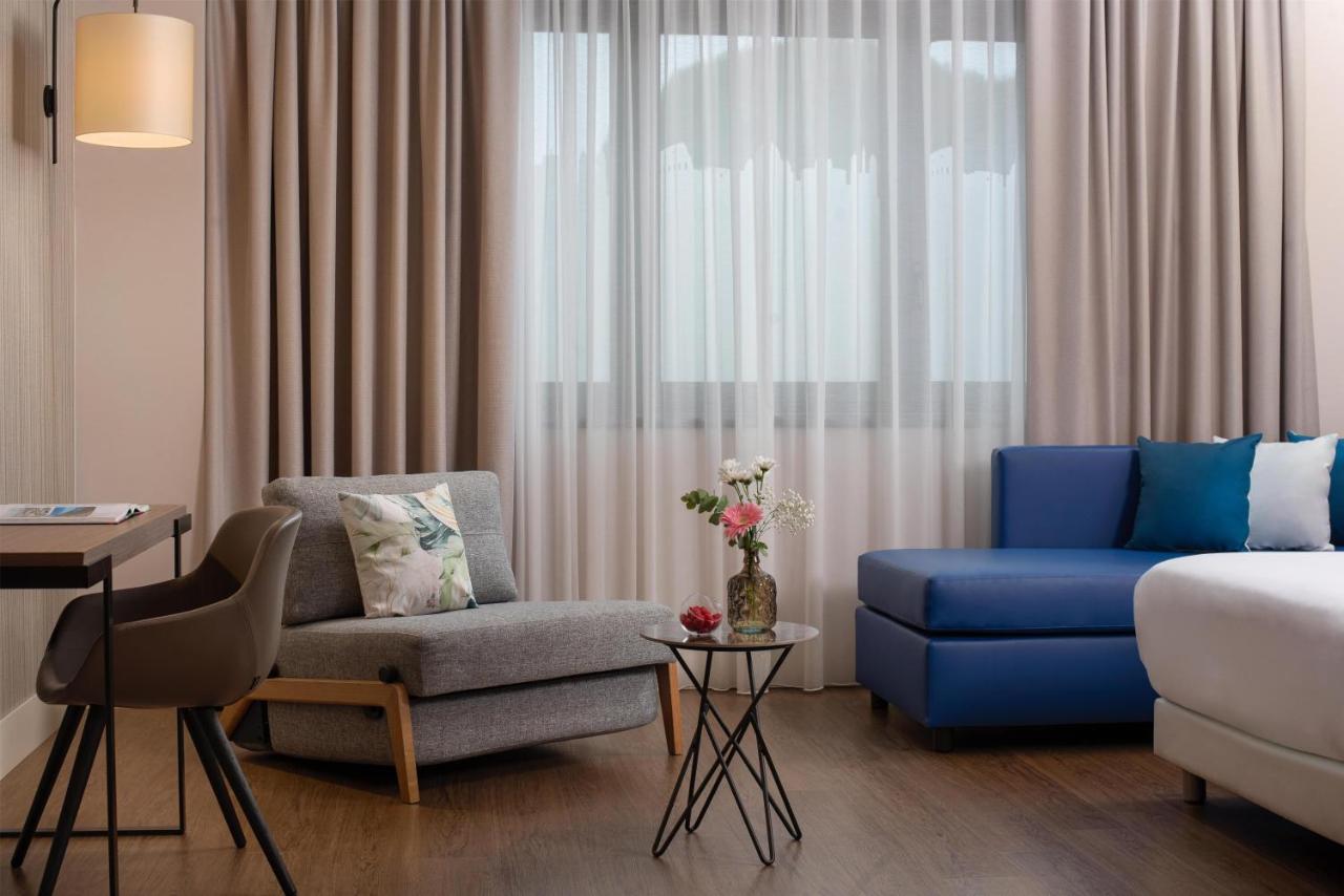 een woonkamer met een blauwe bank en een stoel bij NH Roma Villa Carpegna in Rome