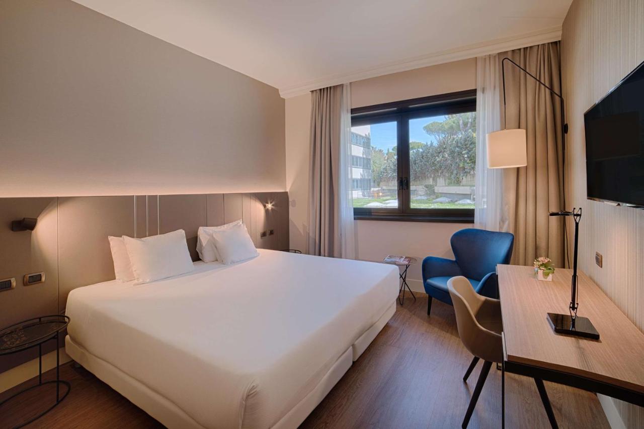 een hotelkamer met een groot wit bed en een bureau bij NH Roma Villa Carpegna in Rome