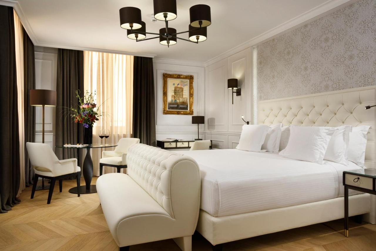 een slaapkamer met een groot wit bed en een tafel met stoelen bij Hotel Splendide Royal - The Leading Hotels of the Worl