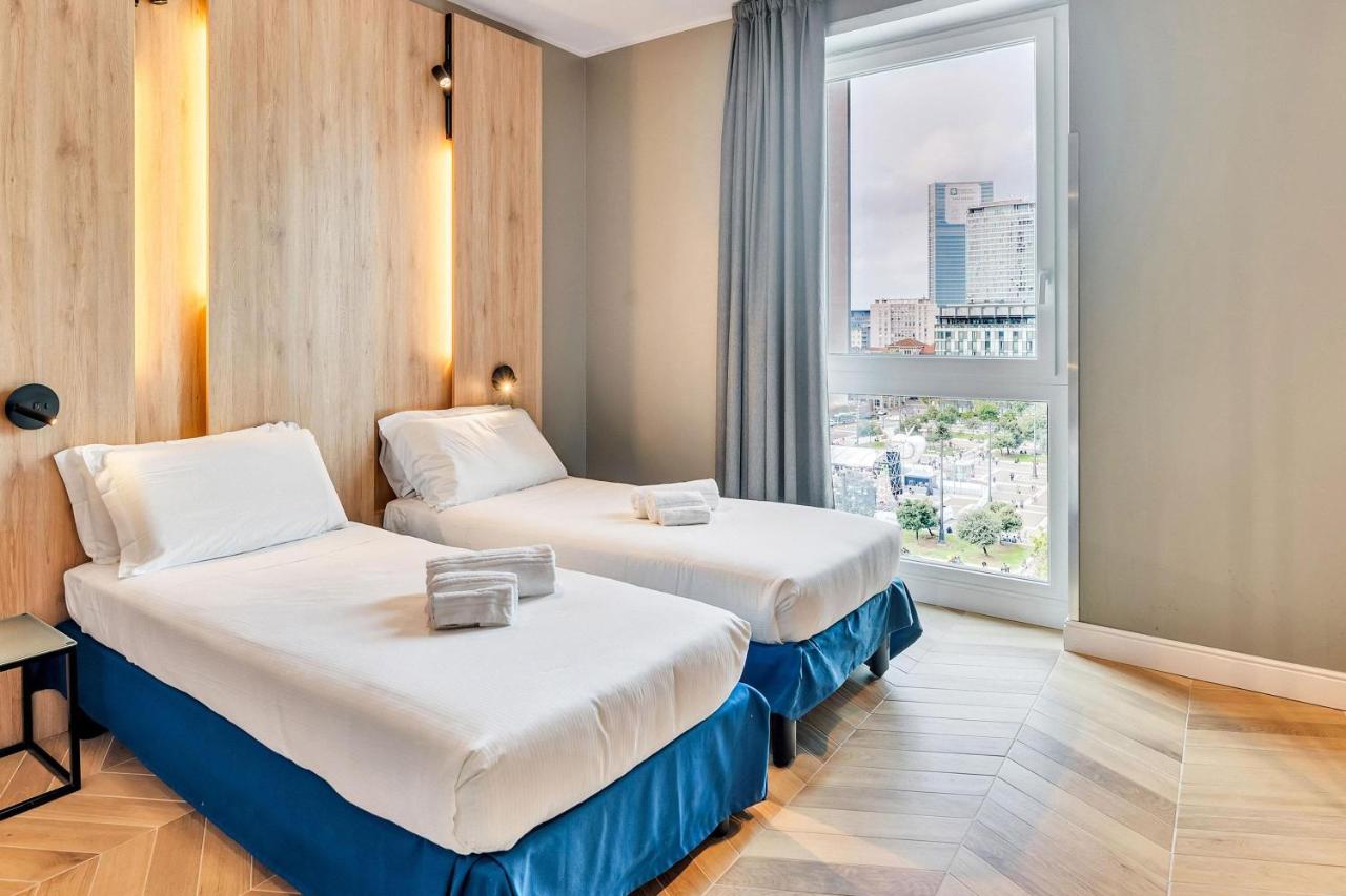 een hotelkamer met twee bedden en een raam bij B&B Hotel Milano Aosta in Milaan