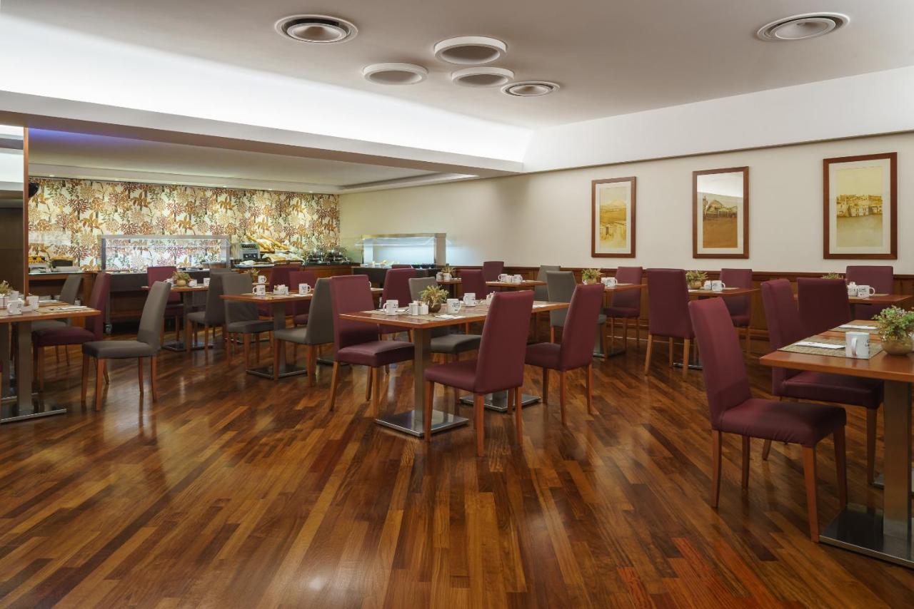 een restaurant met houten vloeren en tafels en stoelen bij Exe Majestic in Napels