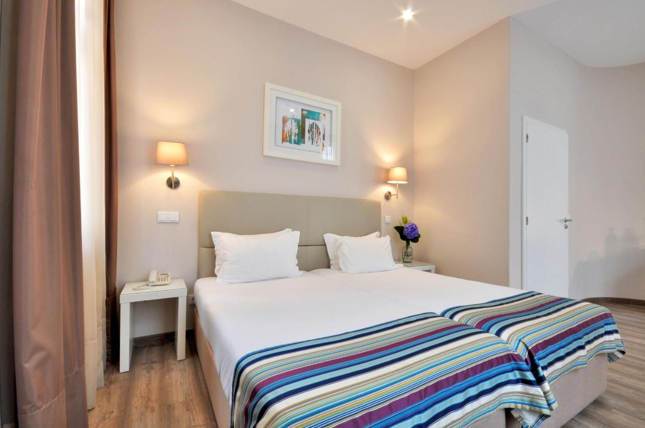 een slaapkamer met een groot wit bed met twee kussens bij Porto Domus Hotel in Porto