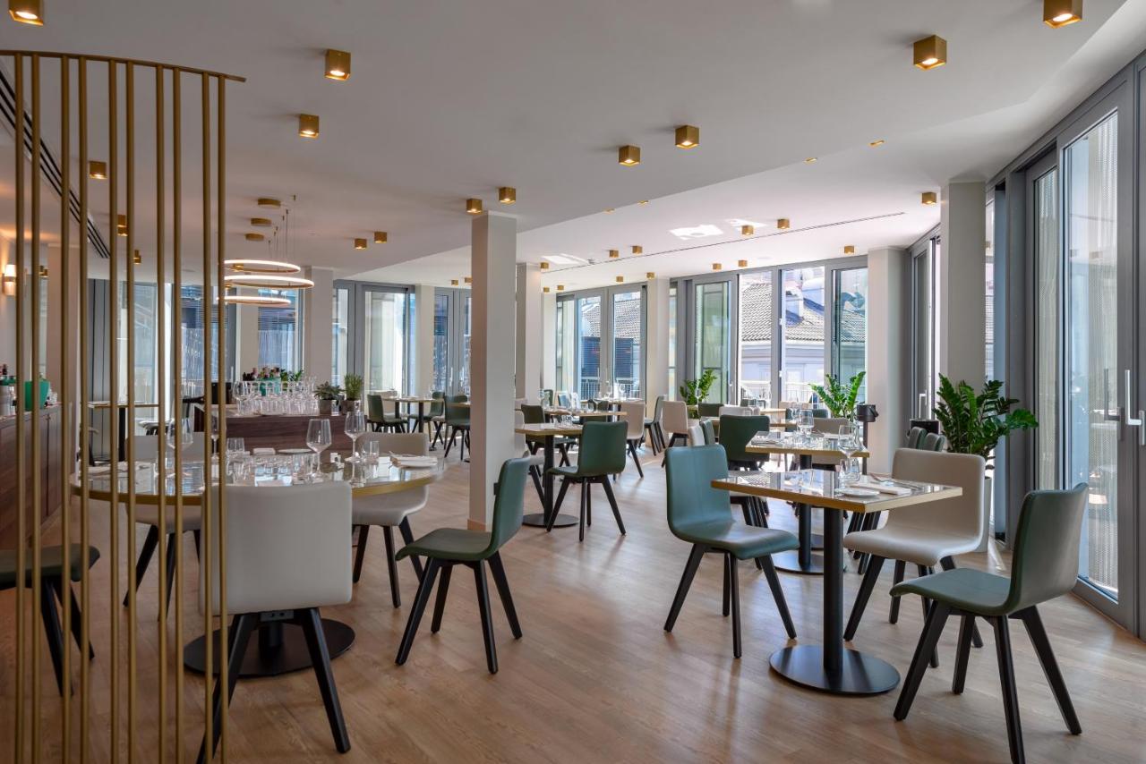 een restaurant met tafels, stoelen en ramen bij Hotel Tocq in Milaan