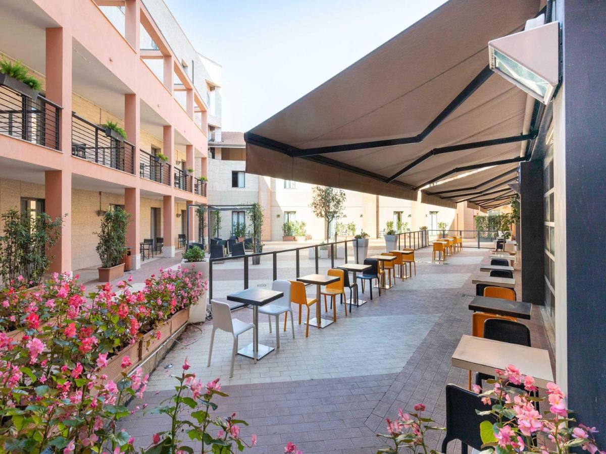 een buitenterras met tafels en stoelen en bloemen bij B&B Hotel Roma Tuscolana San Giovanni in Rome