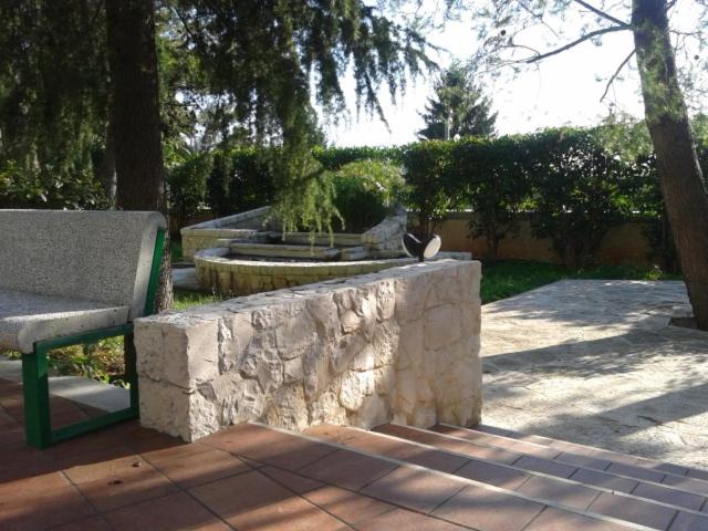 een park met een bankje en een stenen muur bij Hotel Astoria in Alberobello +17 foto's