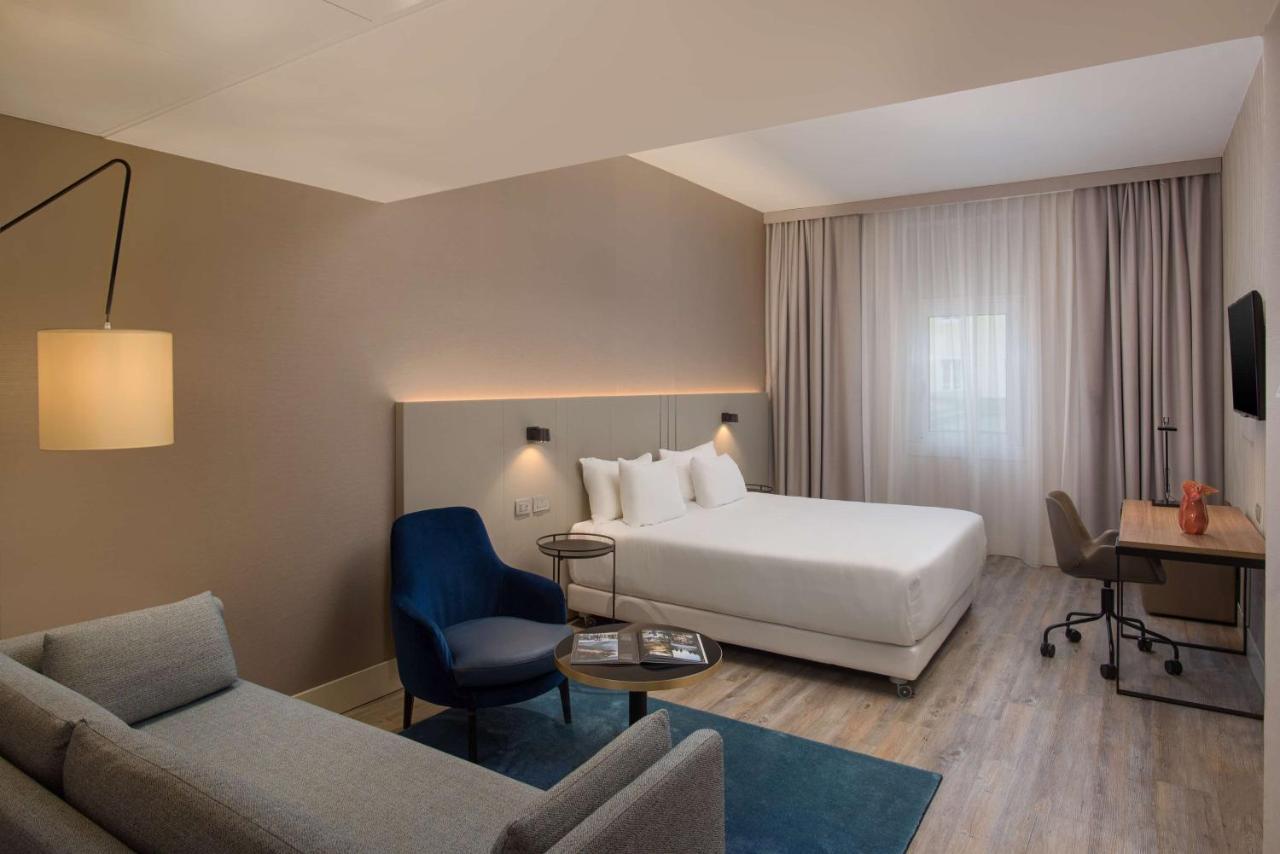 een hotelkamer met een bed en een bank bij NH Trieste in Trieste