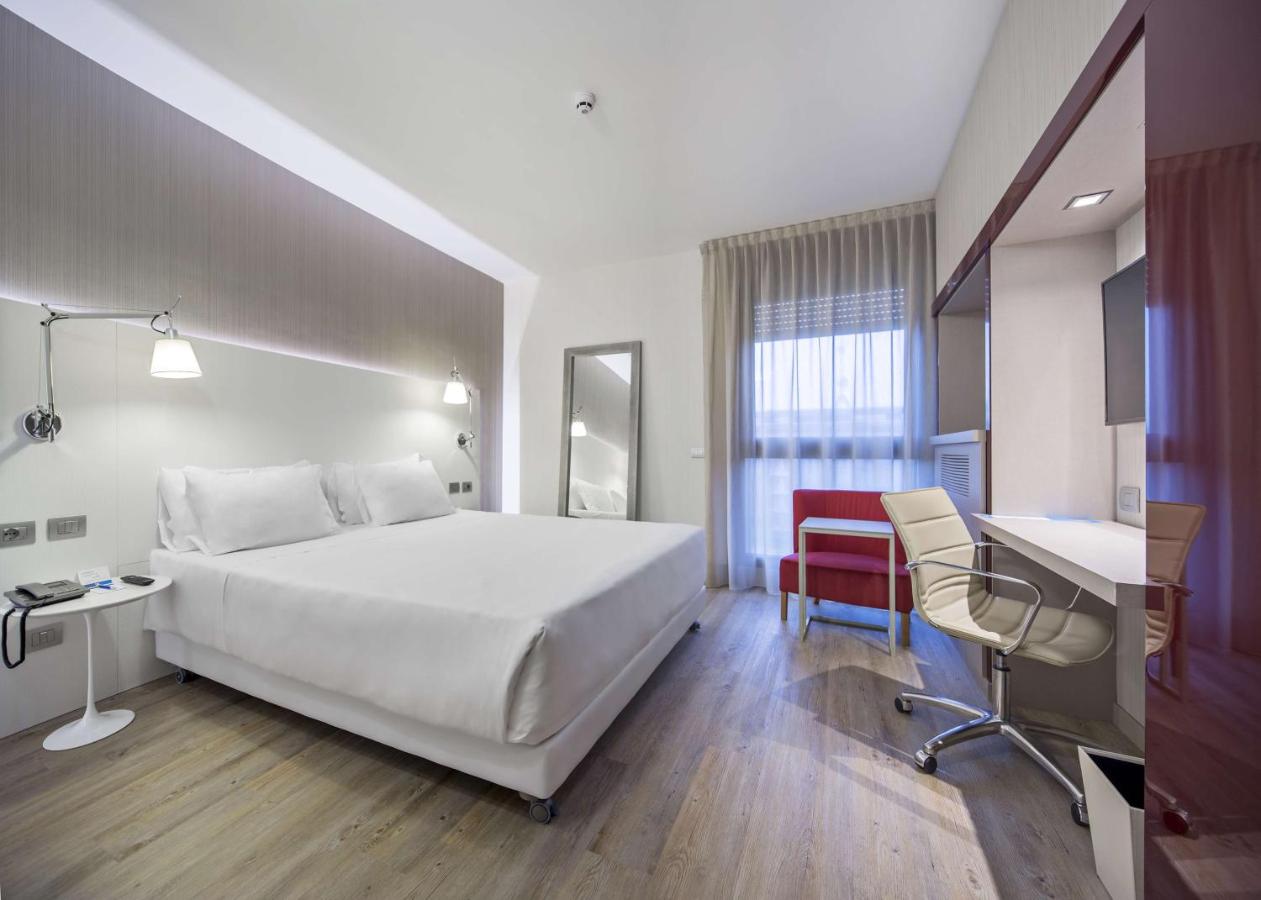 een hotelkamer met een groot wit bed en een bureau bij NH Milano Congress Centre in Assago