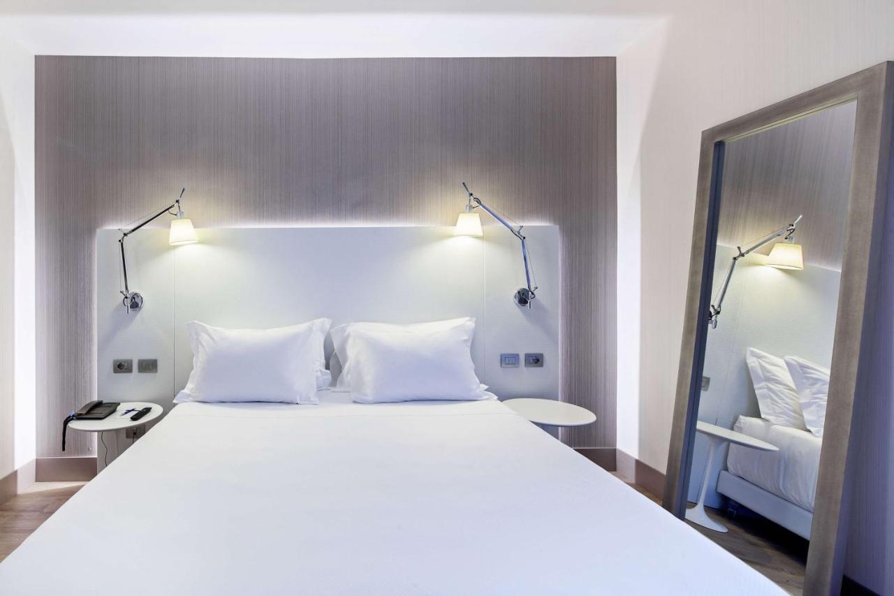 een slaapkamer met een groot wit bed en twee lampen bij NH Milano Congress Centre in Assago