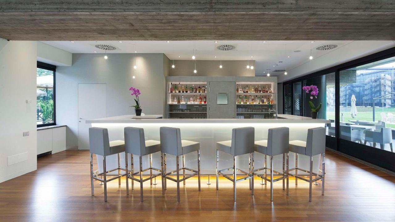 een keuken met een bar met grijze barkrukken bij NH Milano Congress Centre in Assago