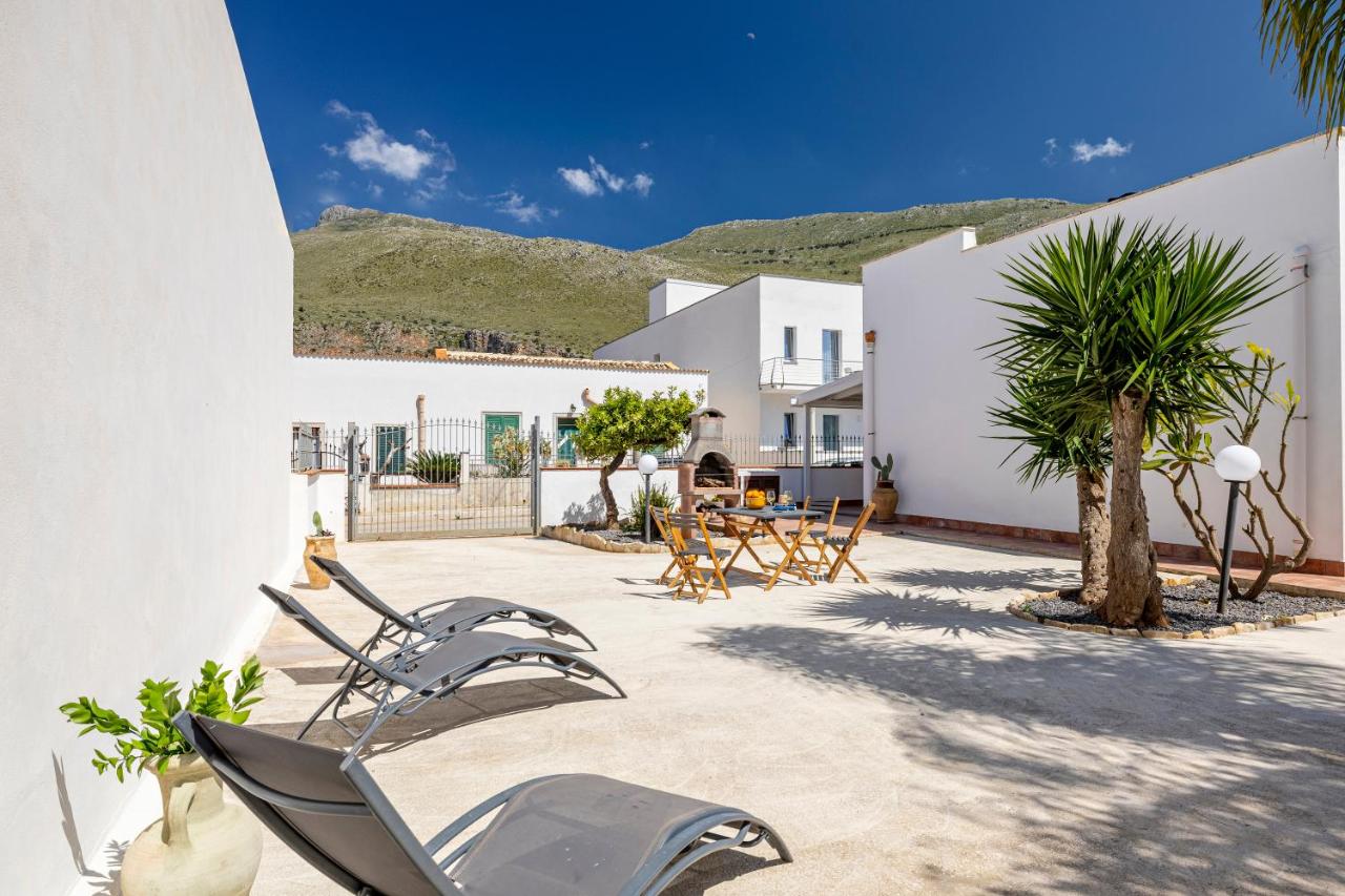 een patio met stoelen en bomen en een gebouw bij Case Vacanza Loria in Castelluzzo